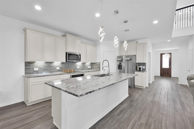 kitchen with a kitchen island with sink, appliances with stainless steel finishes, decorative backsplash, and a sink