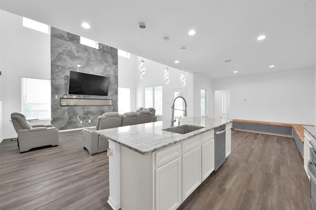 kitchen featuring a sink, white cabinetry, open floor plan, and dishwasher