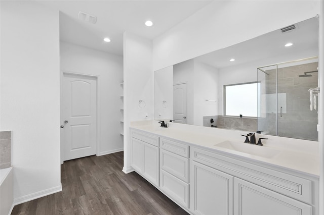 bathroom with double vanity, visible vents, a stall shower, a sink, and wood finished floors