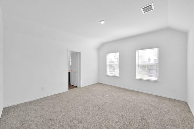 carpeted spare room with lofted ceiling, visible vents, and baseboards