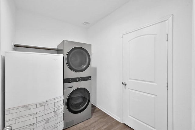 laundry area with stacked washer and dryer, laundry area, and wood finished floors