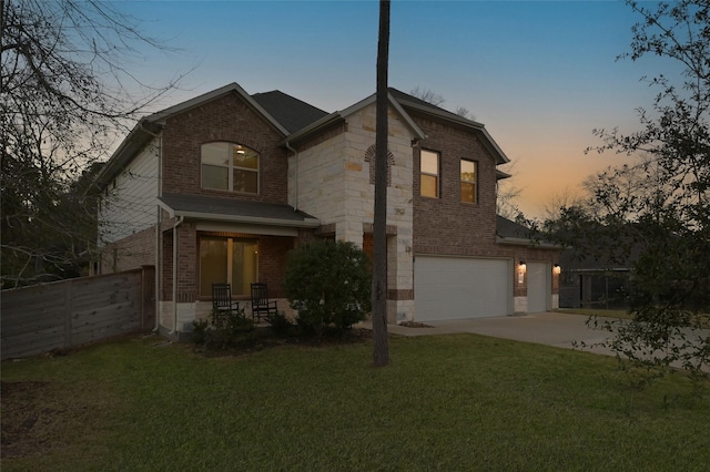 traditional-style home featuring brick siding, concrete driveway, an attached garage, fence, and a front yard