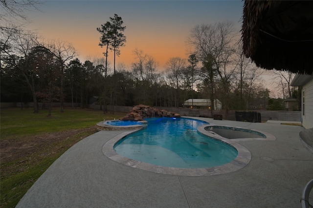 pool at dusk featuring an outdoor pool, a patio area, a yard, and an in ground hot tub