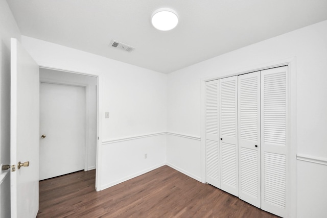 unfurnished bedroom with baseboards, a closet, visible vents, and wood finished floors