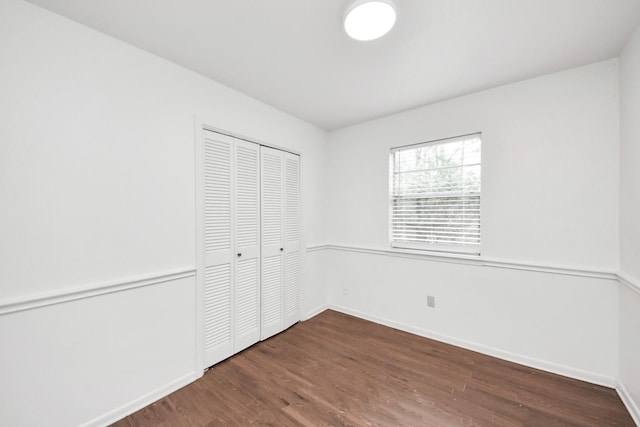 unfurnished bedroom featuring a closet, baseboards, and wood finished floors