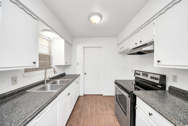 kitchen featuring dark countertops, under cabinet range hood, electric range, and a sink