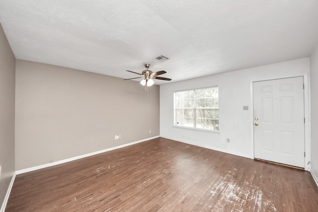 spare room featuring baseboards, a textured ceiling, visible vents, and wood finished floors