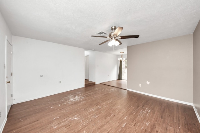 unfurnished room featuring a textured ceiling, visible vents, wood finished floors, and ceiling fan with notable chandelier