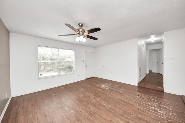 spare room with ceiling fan, a textured ceiling, wood finished floors, and baseboards