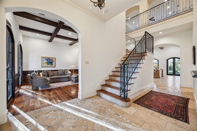 foyer entrance featuring baseboards, arched walkways, a high ceiling, beam ceiling, and recessed lighting