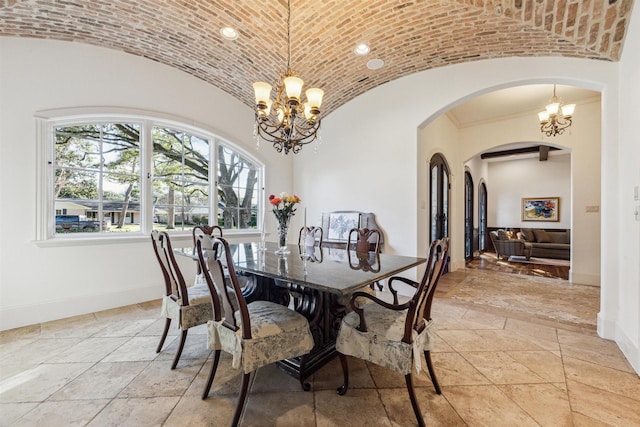 dining room featuring baseboards, brick ceiling, an inviting chandelier, vaulted ceiling, and stone tile flooring