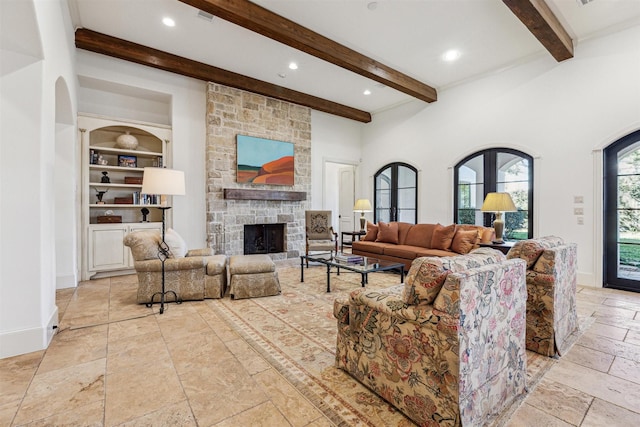 living room featuring built in shelves, beam ceiling, stone tile flooring, and a stone fireplace