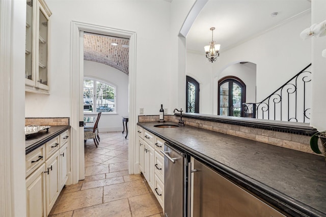 kitchen featuring glass insert cabinets, a sink, baseboards, dark countertops, and stone tile flooring