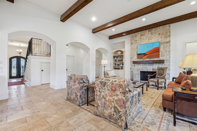 living area featuring arched walkways, a stone fireplace, baseboards, built in features, and beamed ceiling