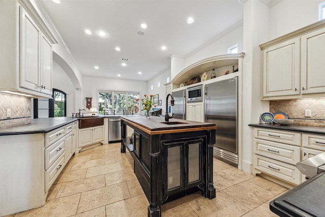 kitchen featuring a peninsula, appliances with stainless steel finishes, arched walkways, and a sink