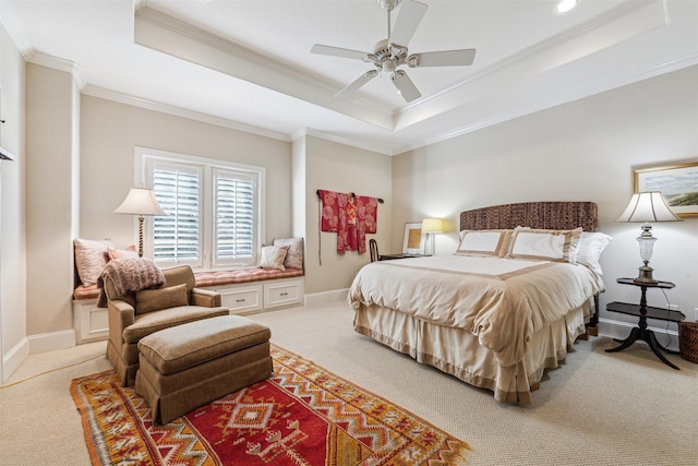 carpeted bedroom with ornamental molding, a tray ceiling, and baseboards