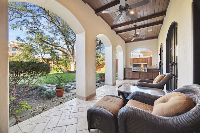 view of patio / terrace featuring ceiling fan, a sink, a grill, fence, and exterior kitchen