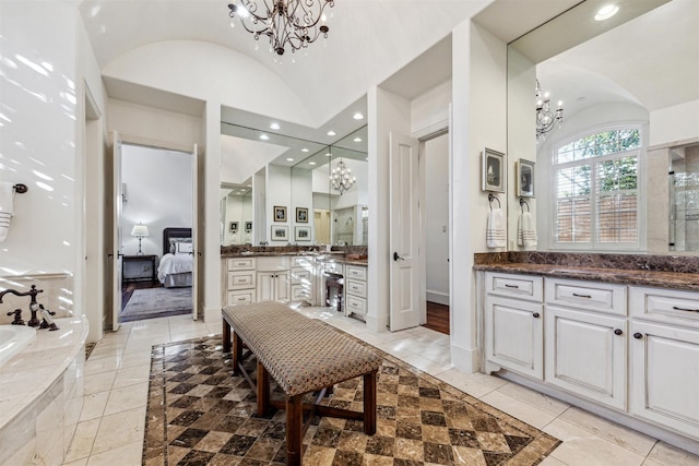 ensuite bathroom featuring a chandelier, vaulted ceiling, vanity, and recessed lighting