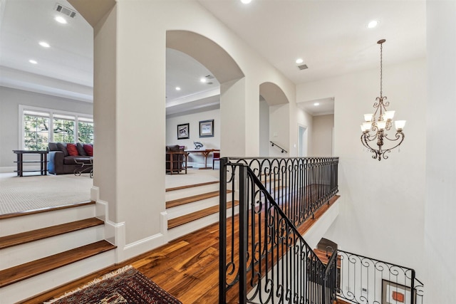 hallway featuring visible vents, arched walkways, wood finished floors, an upstairs landing, and recessed lighting