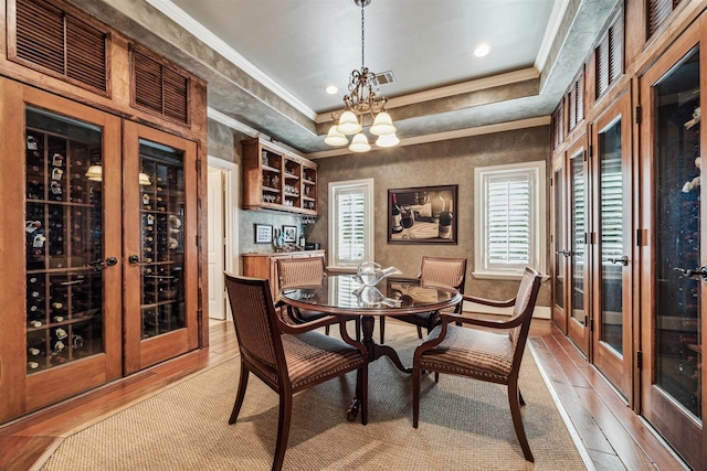 dining area with light wood-type flooring, visible vents, crown molding, and a notable chandelier