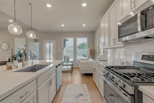 kitchen with hanging light fixtures, white cabinetry, stainless steel appliances, and a sink