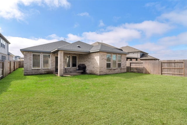 rear view of property with a fenced backyard, a patio, a lawn, and brick siding