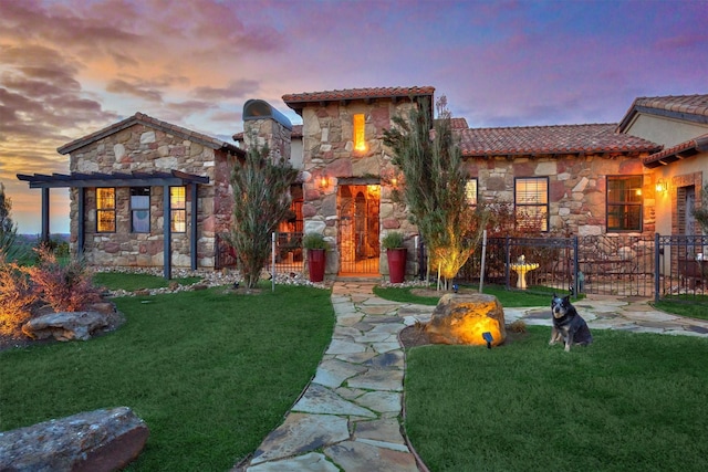 view of front of property featuring a tile roof, fence, stone siding, a yard, and a pergola