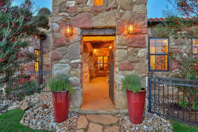 doorway to property with stone siding and fence