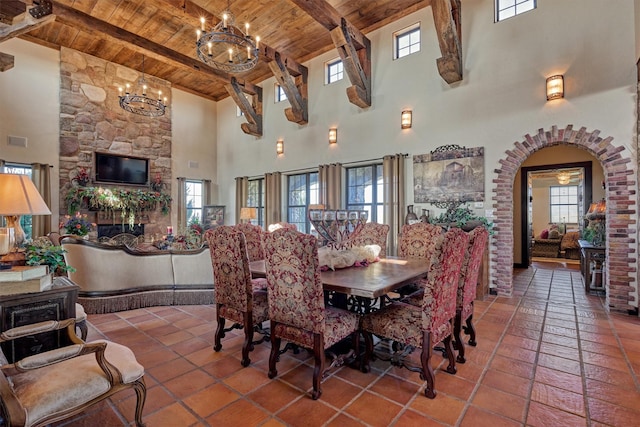 dining area featuring arched walkways, beamed ceiling, wood ceiling, and a healthy amount of sunlight