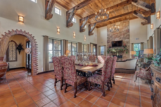 dining area with arched walkways, wood ceiling, a notable chandelier, a healthy amount of sunlight, and beam ceiling