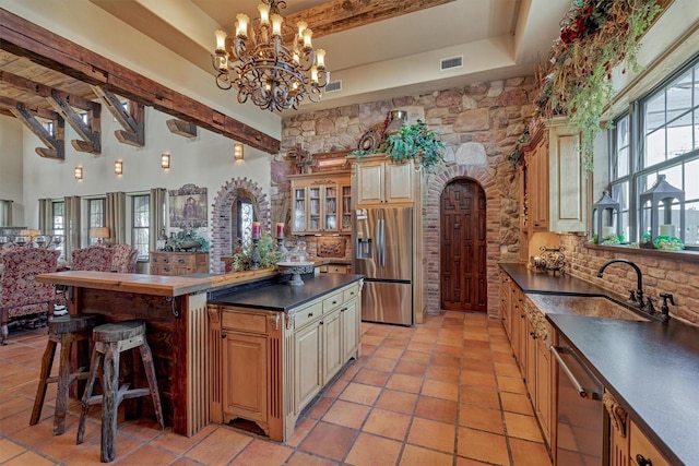 kitchen with arched walkways, stainless steel appliances, a sink, tasteful backsplash, and dark countertops