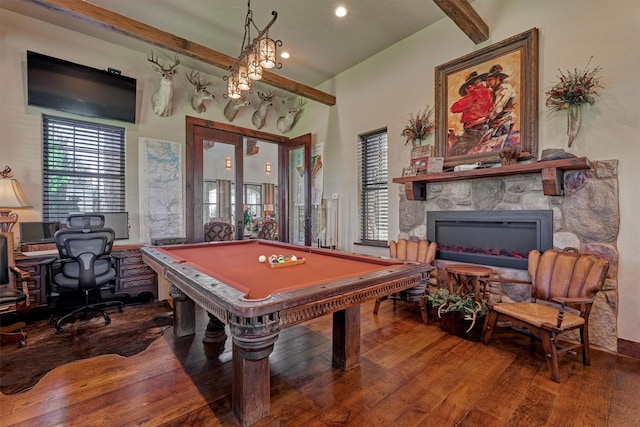 game room with a healthy amount of sunlight, hardwood / wood-style floors, beamed ceiling, and a stone fireplace