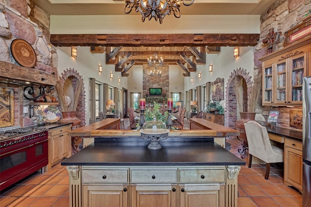 kitchen featuring dark countertops, an inviting chandelier, range with two ovens, and beam ceiling