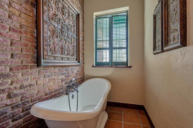 full bath with baseboards, a textured wall, a soaking tub, brick wall, and tile patterned floors