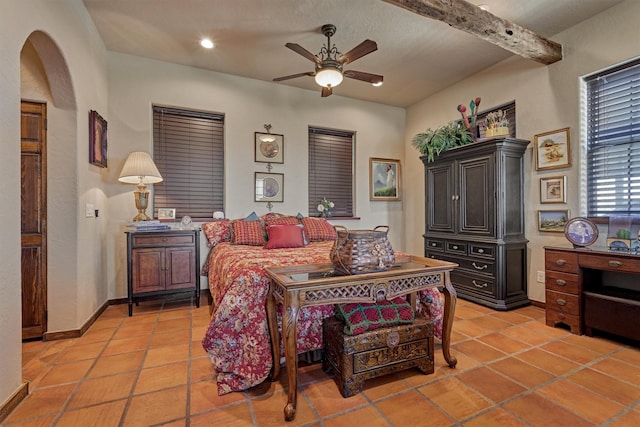 bedroom with light tile patterned floors, arched walkways, beam ceiling, and baseboards