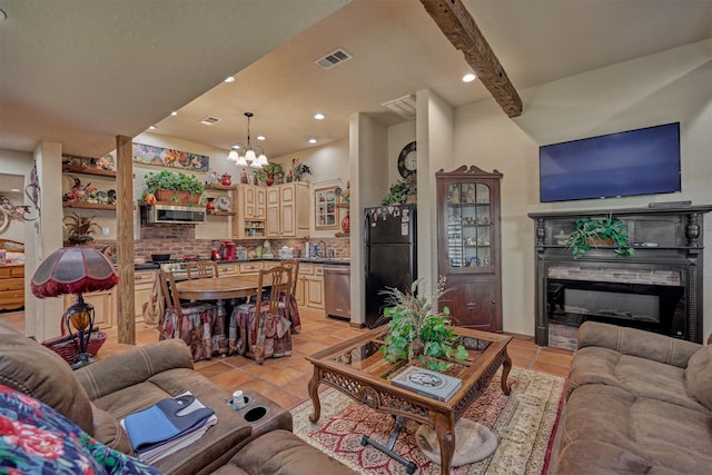 living room featuring beam ceiling, light tile patterned floors, visible vents, a glass covered fireplace, and a chandelier