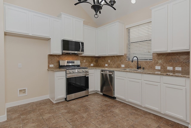 kitchen featuring decorative backsplash, light stone countertops, stainless steel appliances, white cabinetry, and a sink