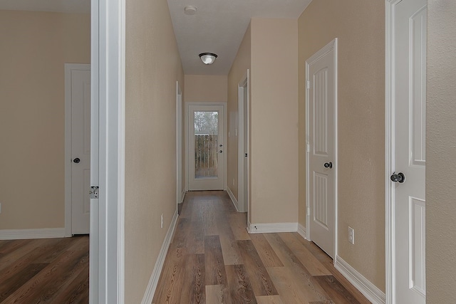 hallway with baseboards and wood finished floors