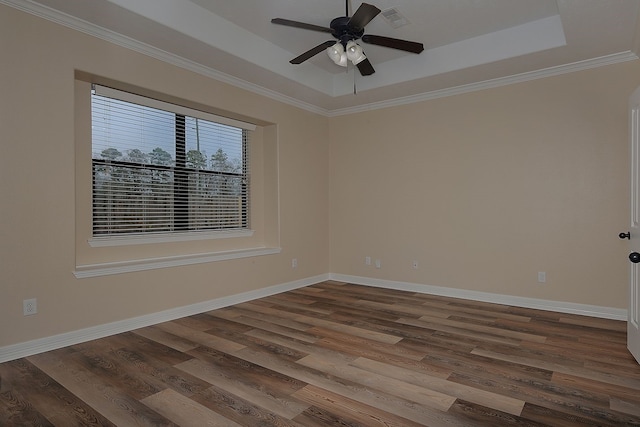 empty room with a tray ceiling, dark wood finished floors, visible vents, and baseboards