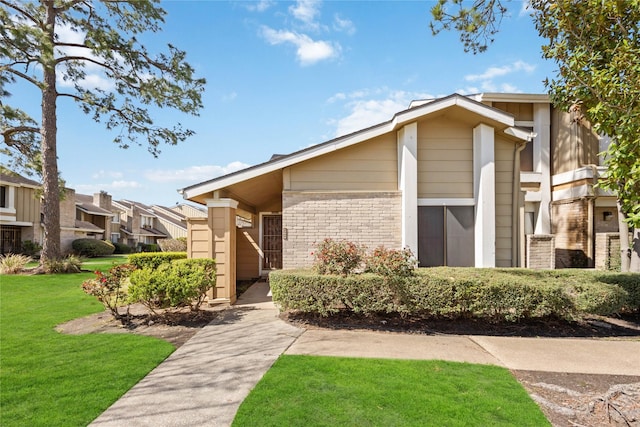 view of front of property featuring a front yard, a residential view, and brick siding