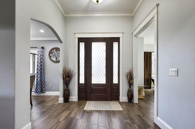 foyer with arched walkways, dark wood-style flooring, crown molding, and baseboards