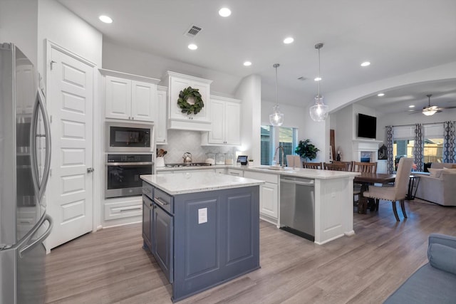 kitchen with open floor plan, stainless steel appliances, white cabinetry, and pendant lighting