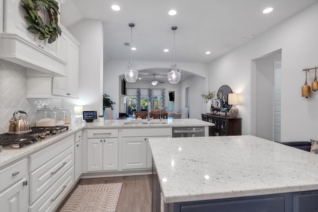 kitchen with arched walkways, pendant lighting, a center island, and a sink