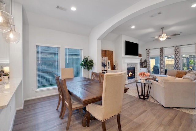 dining space featuring light wood finished floors, a glass covered fireplace, visible vents, and recessed lighting