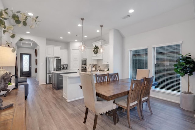 dining space with arched walkways, recessed lighting, visible vents, light wood-type flooring, and baseboards