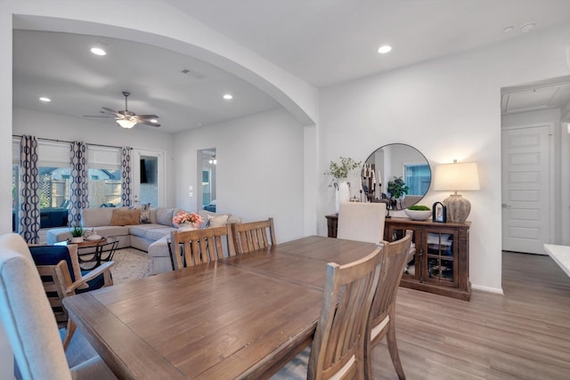 dining area with a ceiling fan, arched walkways, recessed lighting, and wood finished floors