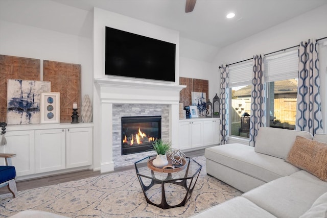 living area featuring recessed lighting, light wood-style flooring, a ceiling fan, and a glass covered fireplace