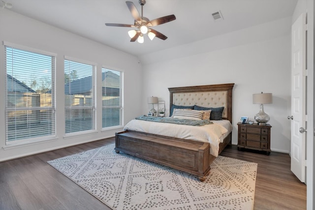 bedroom featuring a ceiling fan, visible vents, vaulted ceiling, and wood finished floors