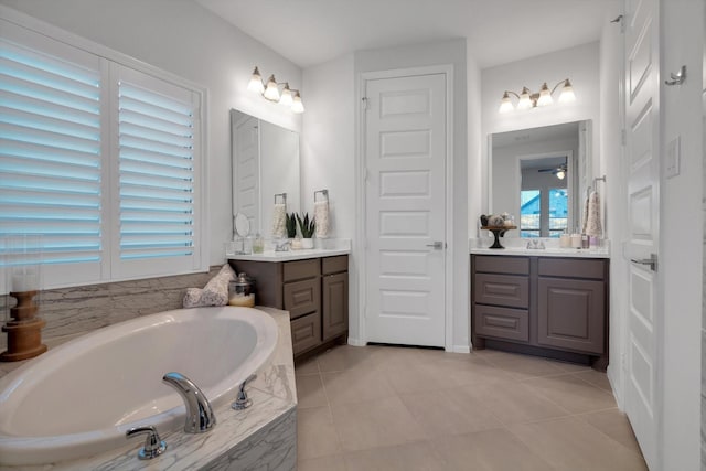 bathroom featuring ceiling fan, two vanities, a garden tub, tile patterned flooring, and a sink