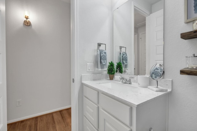 bathroom with wood finished floors, vanity, and baseboards